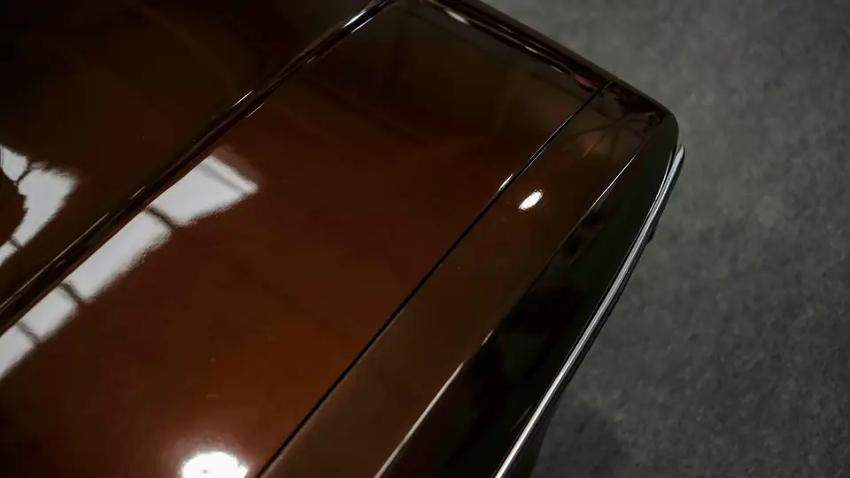 Un capó marrón profundo con las luces del estudio reflejadas nítidas en la pintura