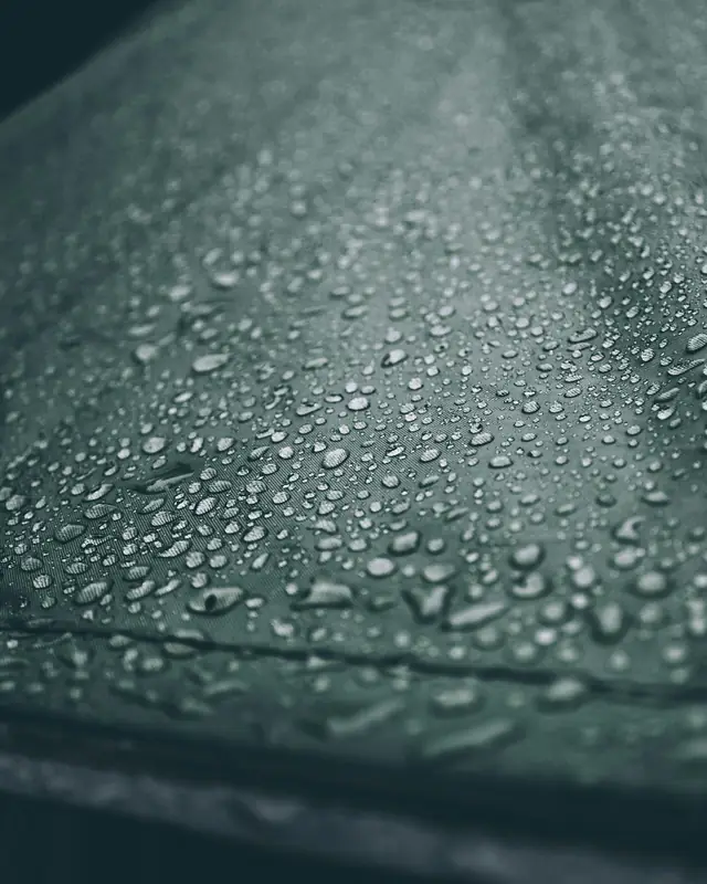 Gotas de agua perladas sobre una superficie oscura tratada