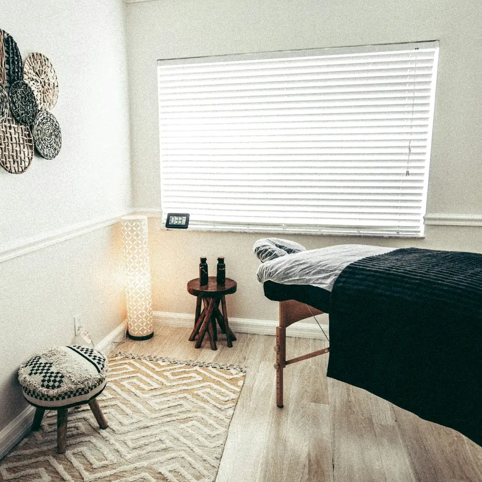 Calm treatment room with a massage table, woven wall plates and a rug