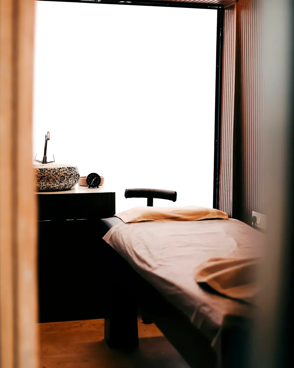 Massage table beside a bright window in a wood-panelled room