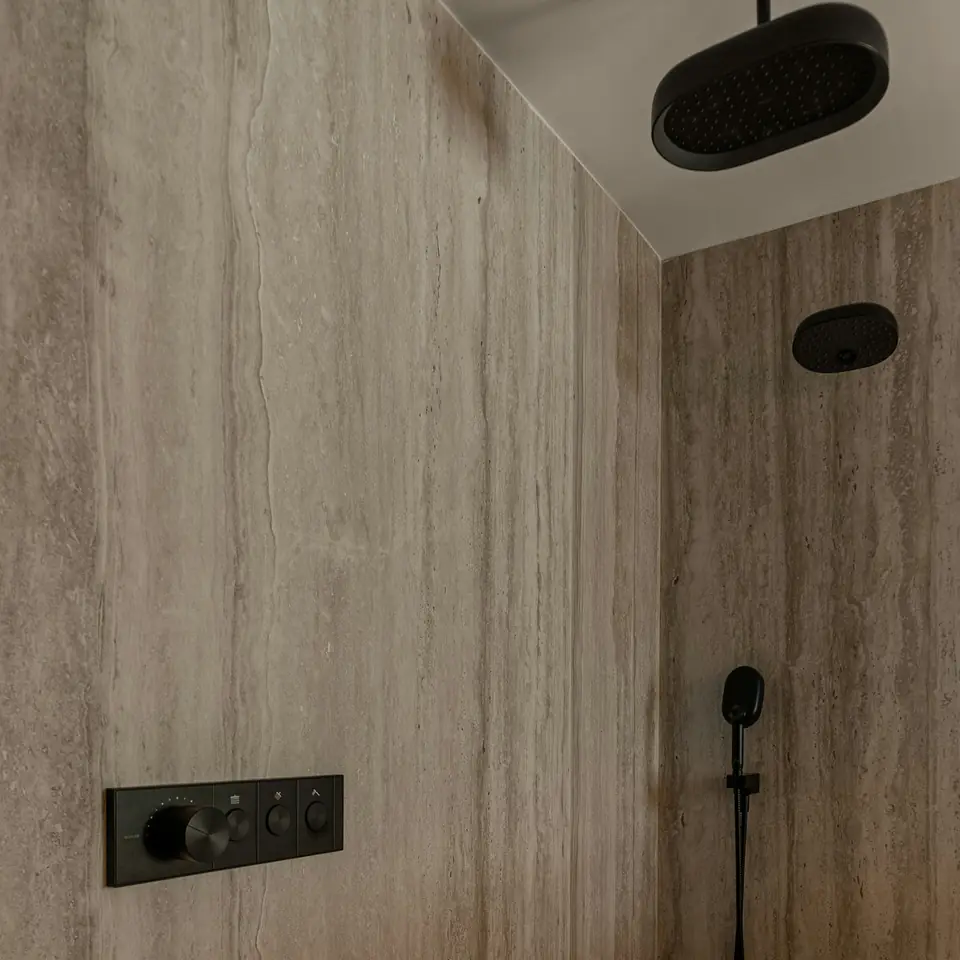 Travertine walk-in shower with a rain head and black fittings