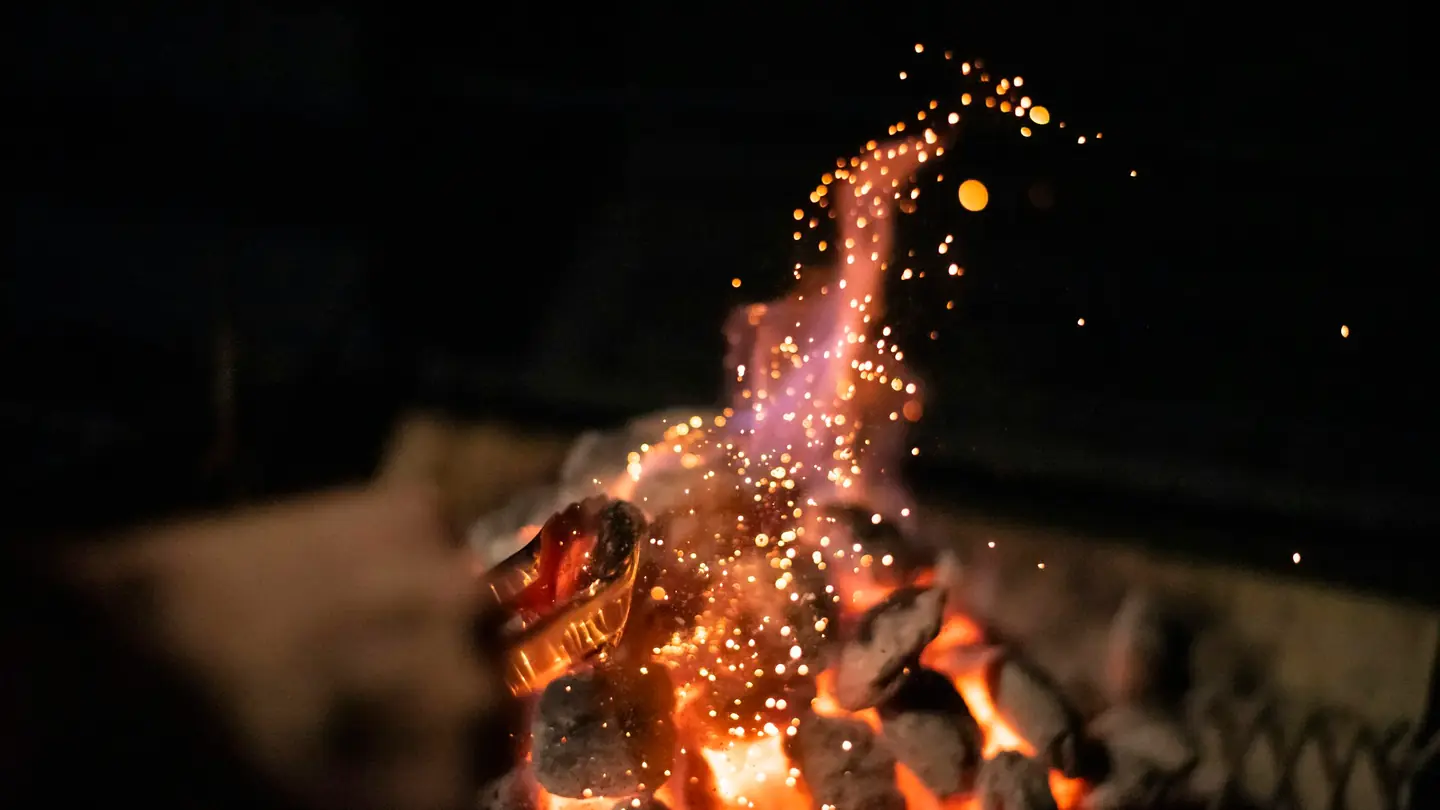 Sparks rising from a charcoal fire in the dark