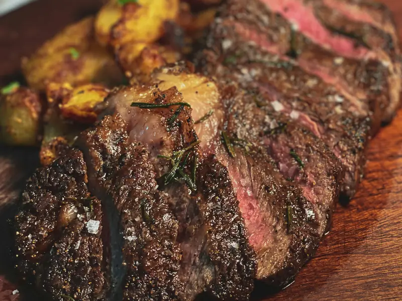 Sliced picanha with its fat cap and crispy potatoes
