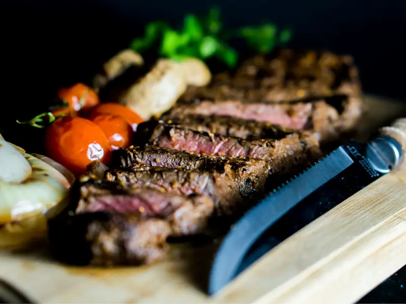 Sliced grilled striploin, pink inside, with roasted tomatoes