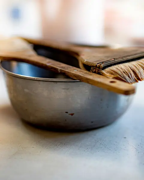 Hair colour brushes resting on a steel mixing bowl