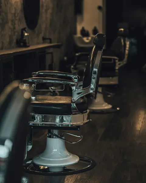 Row of chrome and black leather barber chairs in a dim barbershop