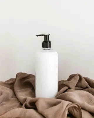 Plain white pump bottle on folded taupe linen