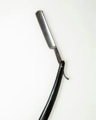Open straight razor with a black handle on a white background
