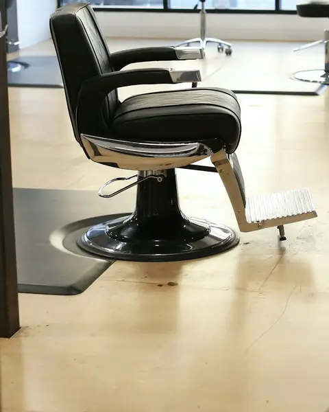 Empty barber chair in a bright studio, seen past the edge of a round mirror