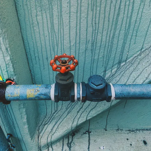 Before: a valve on a pipe with water stains running down the wall