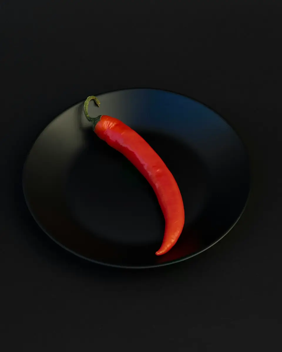 Una guindilla roja sobre un plato negro