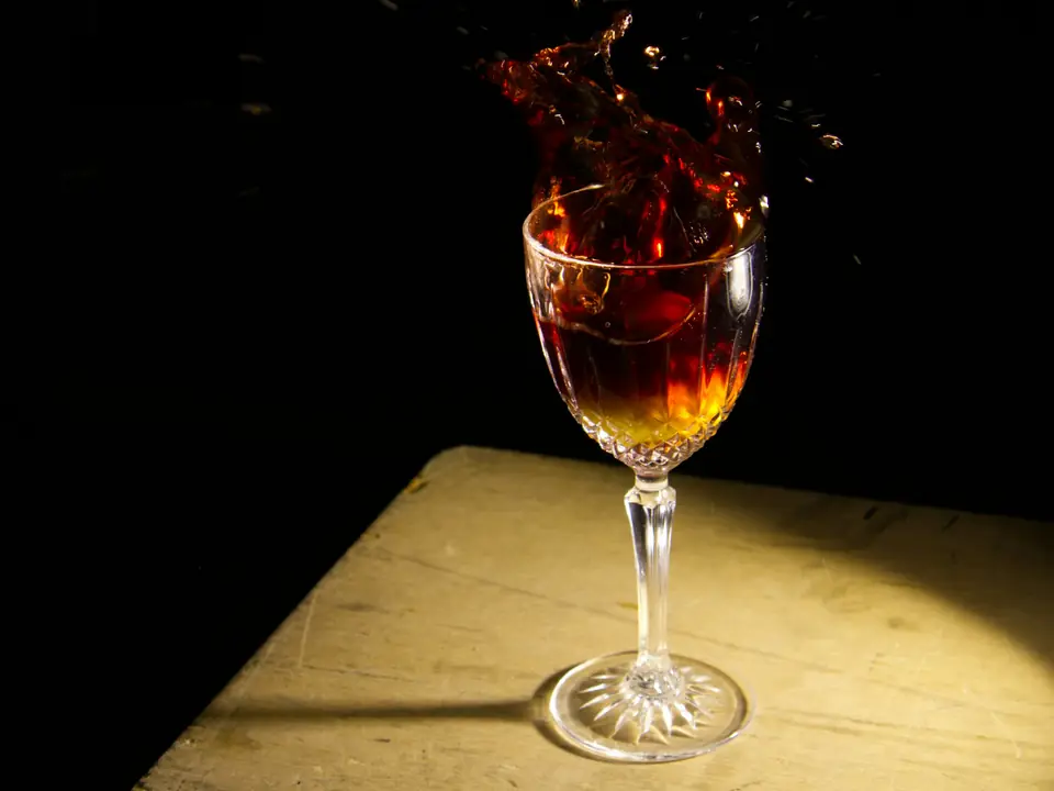 Vino tinto en movimiento en una copa de cristal bajo un único foco