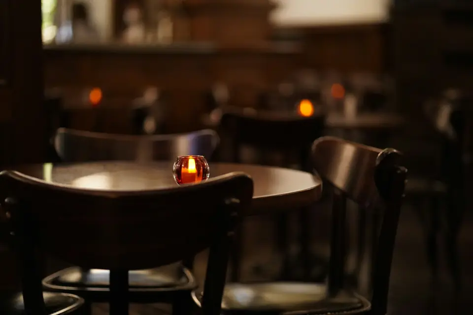 Una vela encendida sobre una mesa vacía por la noche
