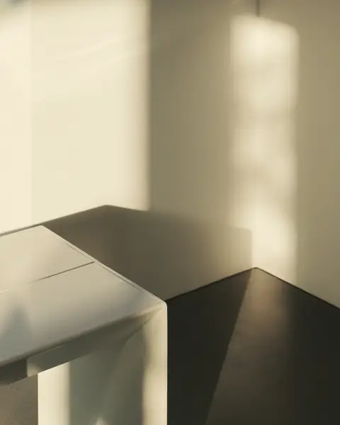 Rincón de escritorio blanco con luz cálida de mañana en la pared