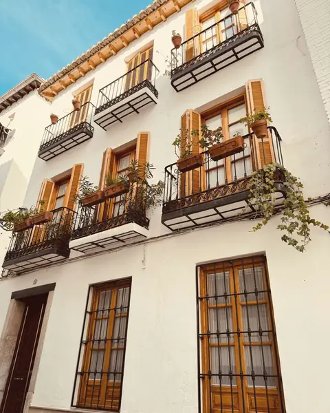 White townhouse facade with wooden shutters and iron balconies